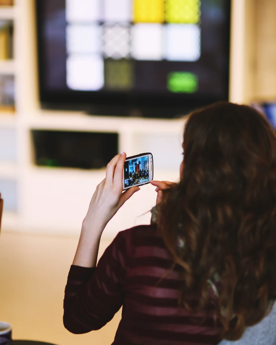 Woman using her phone beside a television