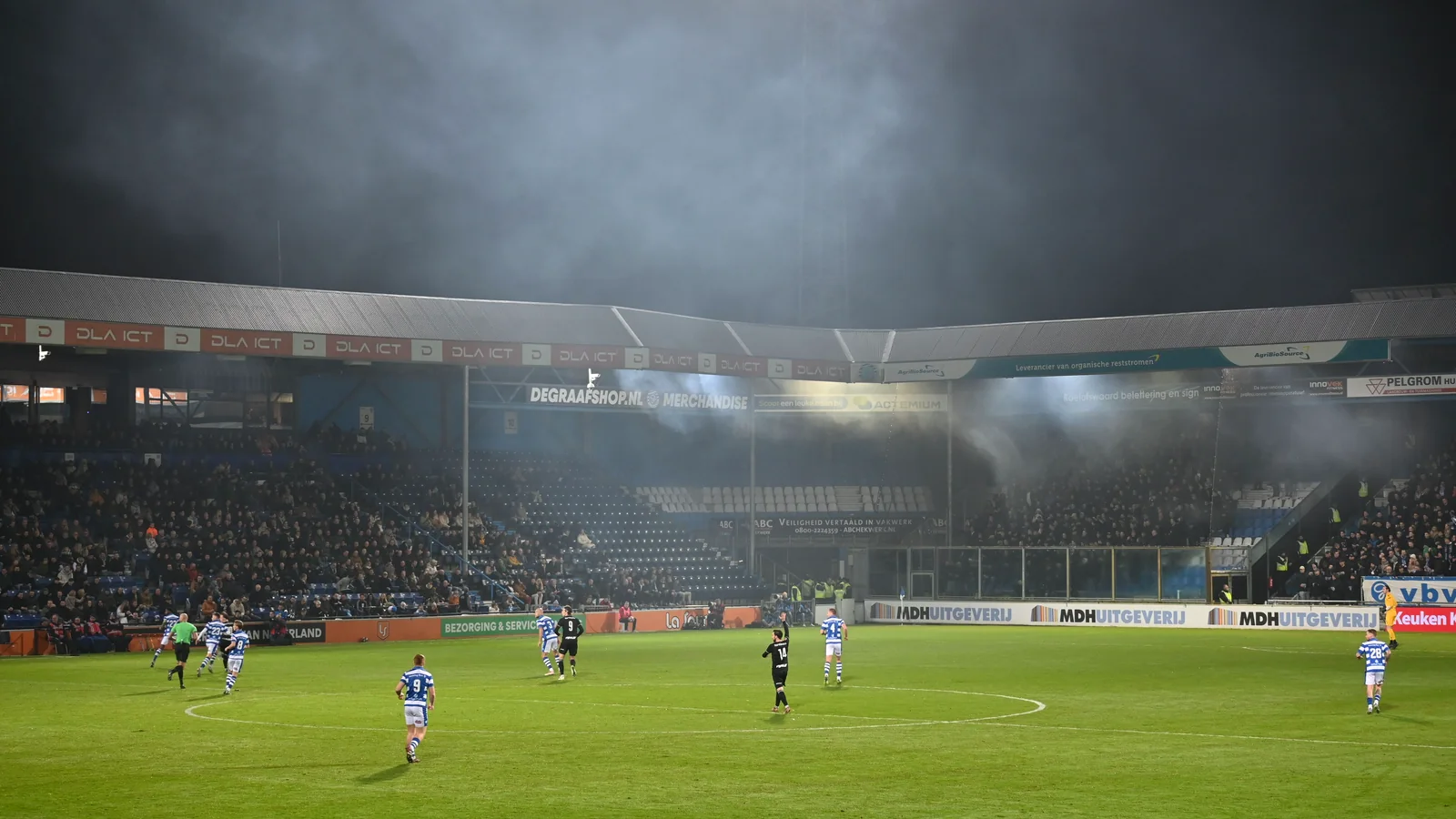 Large football stadium at night with players and supporters